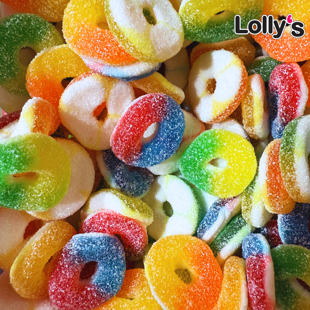 Image d'un assortiment d’anneaux gélifiés bicolores (rouge/bleu, jaune/vert, orange/jaune) avec un enrobage de sucre acidulé qui leur donne un effet brillant et appétissant.