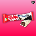 La barre chocolatée Kit Kat Chunky Black and White est disposée sur un fond rose. La gourmandise est une gaufrette couverte de chocolat noir et enrobée de chocolat blanc pour plus de douceurs. 