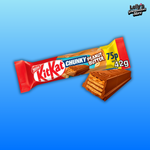 L'image montre la célèbre barre chocolatée kit kat peanut butter disposée sur un fond bleu. Une image de la barre chocolatée croquée nous permet de voir sa composition. 