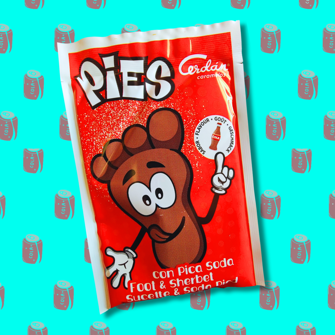 Sucette pied saveur cola emballée dans un sachet rouge illustré par un petit bonhomme en forme de pied et de couleur marron (cola). Sachet disposé sur un fond bleu vif parsemé de canettes de cola rouge. 