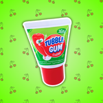 Image d'un tube imitation dentifrice avec un chewing-gum à l'intérieur goût cerise. Le tube est vert avec un bouchon rouge. Sur celui-ci on peut voir un petit bonhomme en forme de liquide de dentifrice qui fait une bulle pour rappeler le chewing-gum. Le tube est posé sur un fond vert fluo avec plein de cerises. 